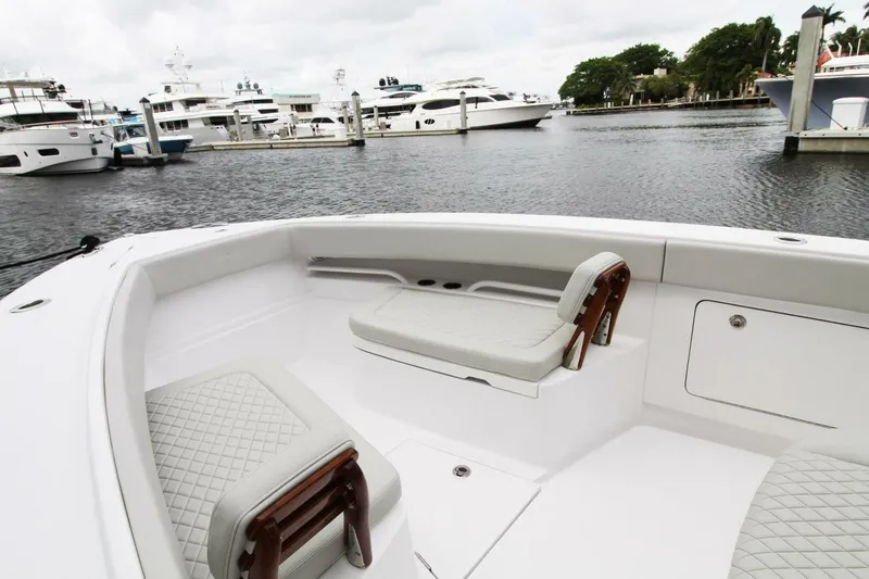 Slide: The Image of 2024 Jupiter 34 HFS boat interior with cushioned seating, docked near luxury yachts. - 11