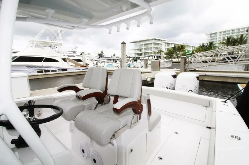 Slide: The Image of 2024 Jupiter 34 HFS boat interior with dual seats and marina background. - 5