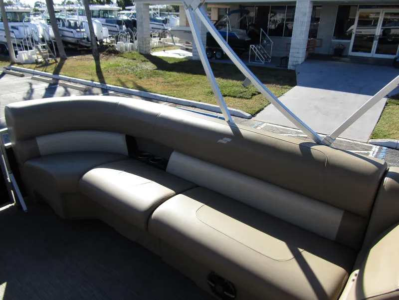 Slide: The Image of 2024 Starcraft LX 20 R pontoon boat with beige seating in a marina setting. - 18