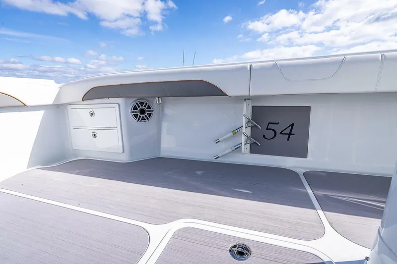 Slide: The Image of 2024 Yellowfin 54 Offshore boat deck with storage and speaker, under clear blue sky. - 20