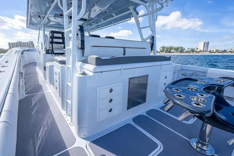 Slide: The Image of 2024 Yellowfin 54 Offshore boat interior with seating and rod holders, cruising on blue ocean. - 21