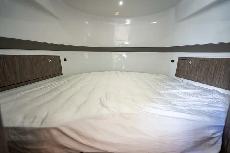 Slide: The Image of 2024 Yellowfin 54 Offshore cabin interior with a spacious bed and wooden storage cabinets. - 32