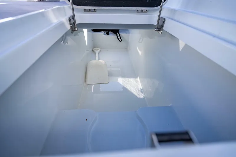 Slide: The Image of 2024 Yellowfin 54 Offshore storage compartment with a white shovel inside. - 39
