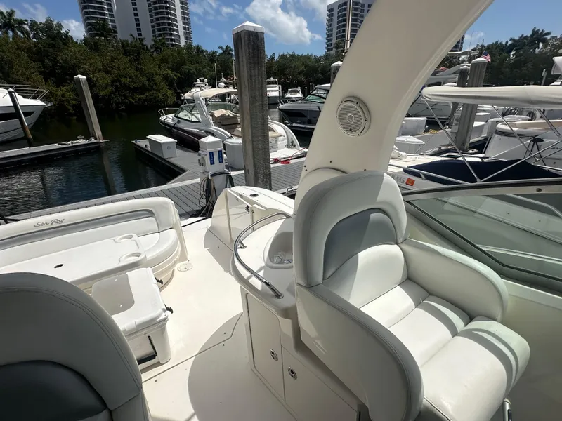 Slide: The Image of 2004 Sea Ray 340 Sundancer yacht interior at marina, featuring white seating and docked boats. - 18