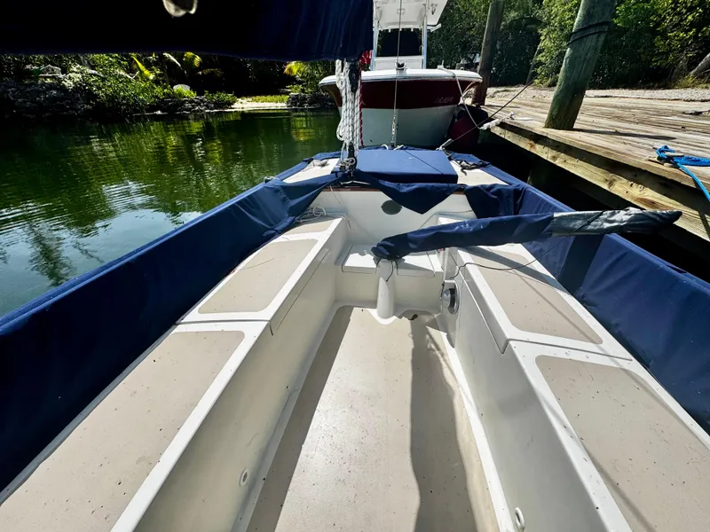 Slide: The Image of 1968 Sailboat 24 with blue covers docked by a serene waterfront. - 10
