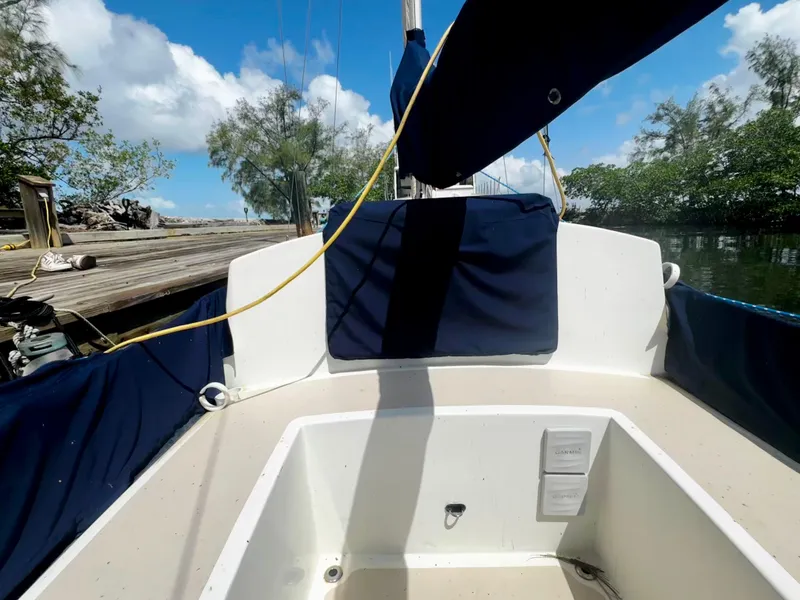 Slide: The Image of 1968 Sailboat 24 cockpit with blue covers, docked near lush greenery and clear sky. - 11