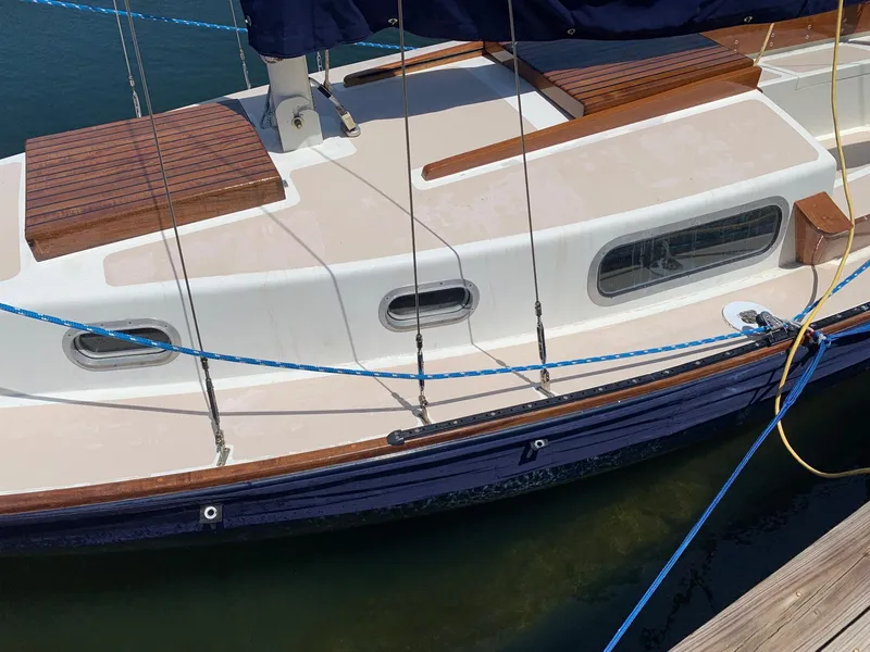 Slide: The Image of 1968 Sailboat 24 docked, featuring wooden deck and blue hull. - 4