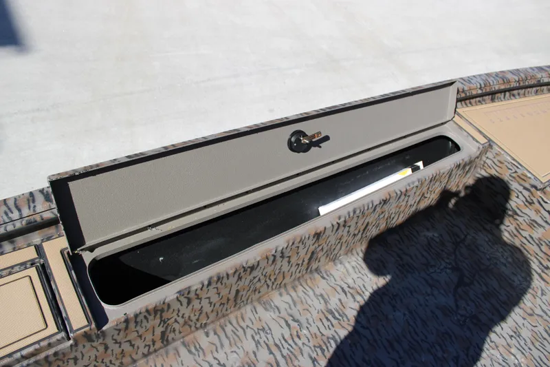 Slide: The Image of 2026 Xpress X18DB boat storage compartment with key lock, open lid, and camouflage design. - 11