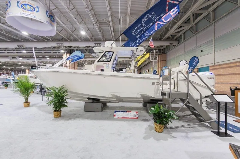Slide: The Image of 2026 Solace 30 CS boat displayed at an indoor exhibition with banners and plants. - 10