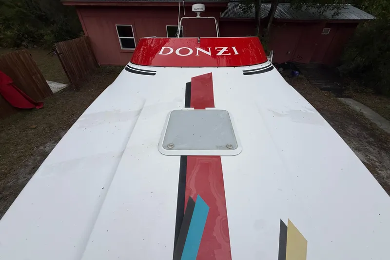 Slide: The Image of 1998 Donzi 33 ZX boat with colorful graphics, parked near a red building. - 56