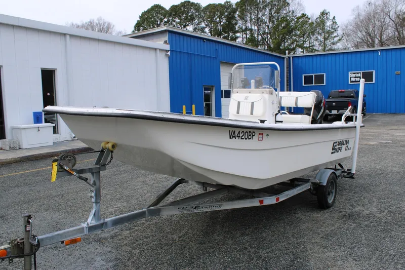 Slide: The Image of 2009 Carolina Skiff 17 DLX boat on trailer, parked near blue building. - 3