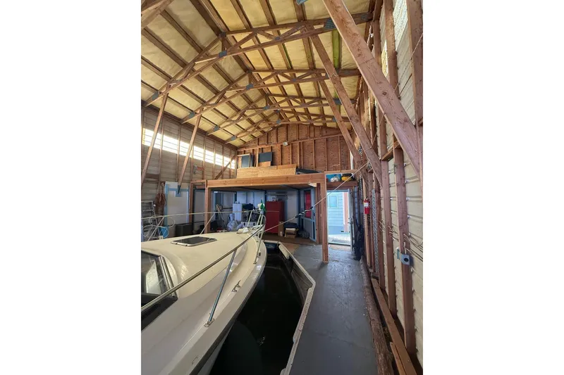 Slide: The Image of Interior of a 1940 custom boathouse with wooden beams and a docked boat. - 13