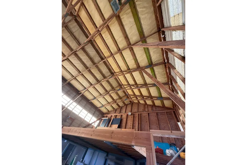 Slide: The Image of Interior view of a 1940 custom boathouse with exposed wooden beams and insulation. - 14