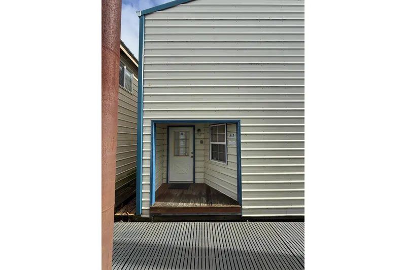 Slide: The Image of Custom 1940 boathouse with white siding and blue trim, featuring a wooden entrance. - 3