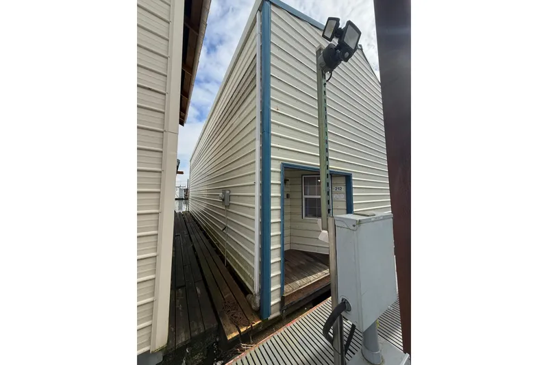 Slide: The Image of 1940 custom boathouse with white siding and blue trim, dockside view. - 4