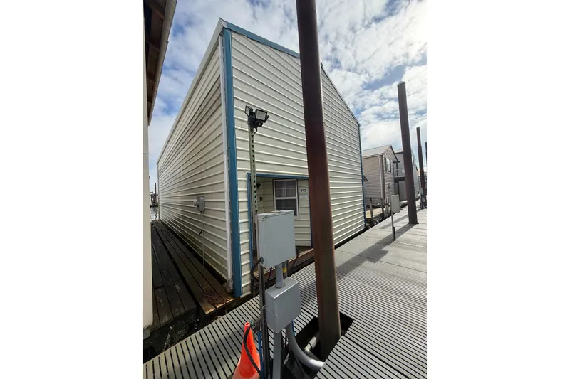 Slide: The Image of Custom 1940 boathouse with metal siding, dockside view under a partly cloudy sky. - 5