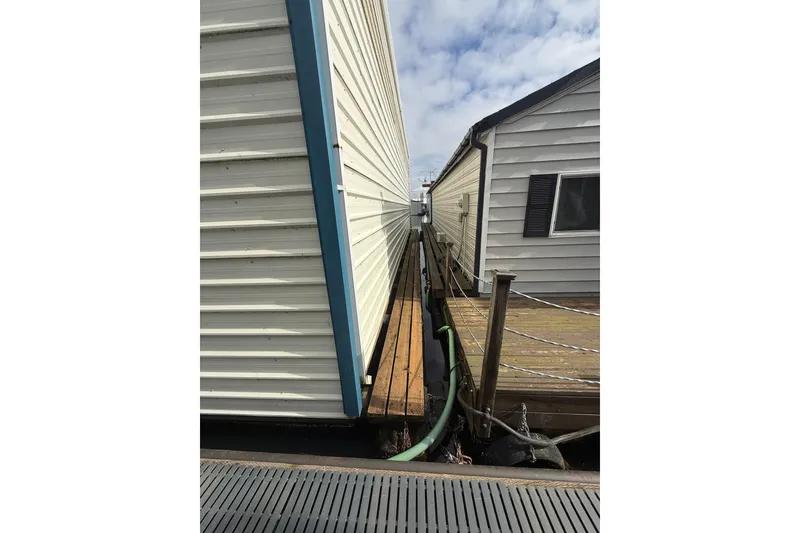 Slide: The Image of Narrow walkway between two 1940 Custom Boathouses under a cloudy sky. - 7