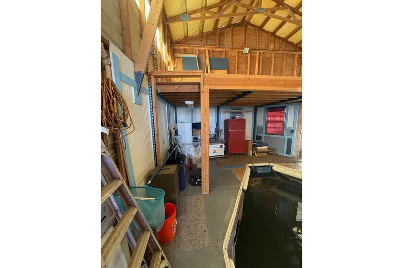 Slide: The Image of 1940 custom boathouse interior with wooden beams, storage, and water access. - 9