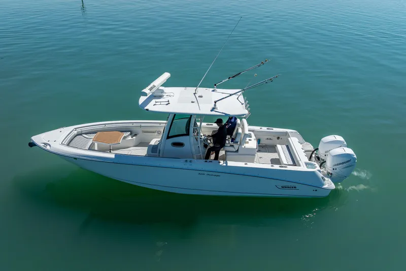 Slide: The Image of 2013 Boston Whaler 320 Outrage boat on calm water, featuring dual outboard engines. - 10