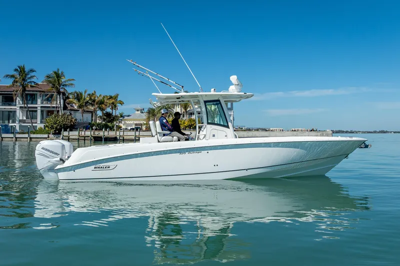 Slide: The Image of 2013 Boston Whaler 320 Outrage boat on calm water, with palm trees in background. - 12