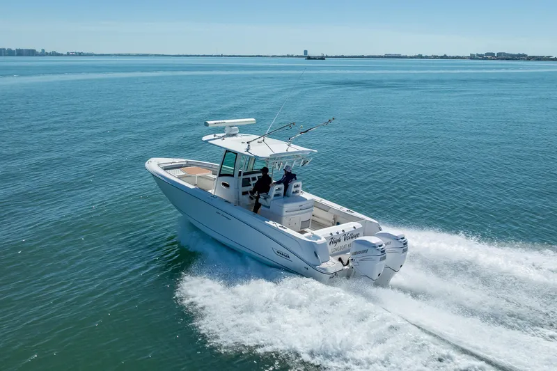 Slide: The Image of 2013 Boston Whaler 320 Outrage cruising on open water, showcasing powerful twin engines. - 13