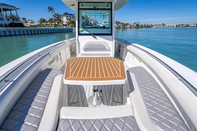Slide: The Image of 2013 Boston Whaler 320 Outrage boat interior with elegant seating and table on calm water. - 19