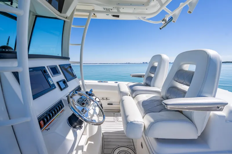 Slide: The Image of 2013 Boston Whaler 320 Outrage helm with luxurious seating and modern controls on calm water. - 25