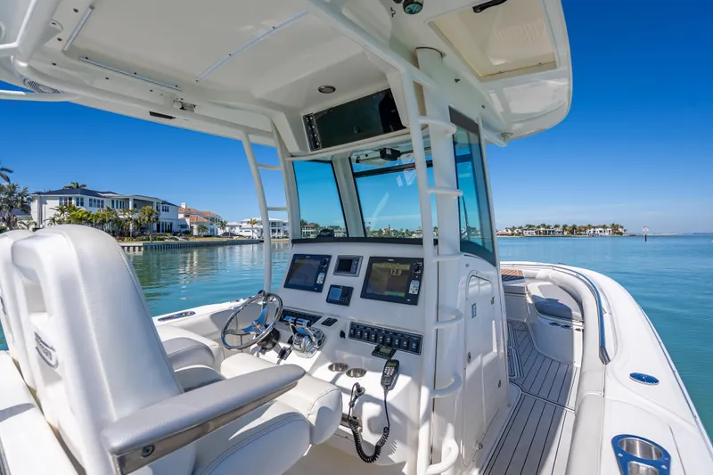 Slide: The Image of 2013 Boston Whaler 320 Outrage boat interior with modern controls, docked by waterfront homes. - 27