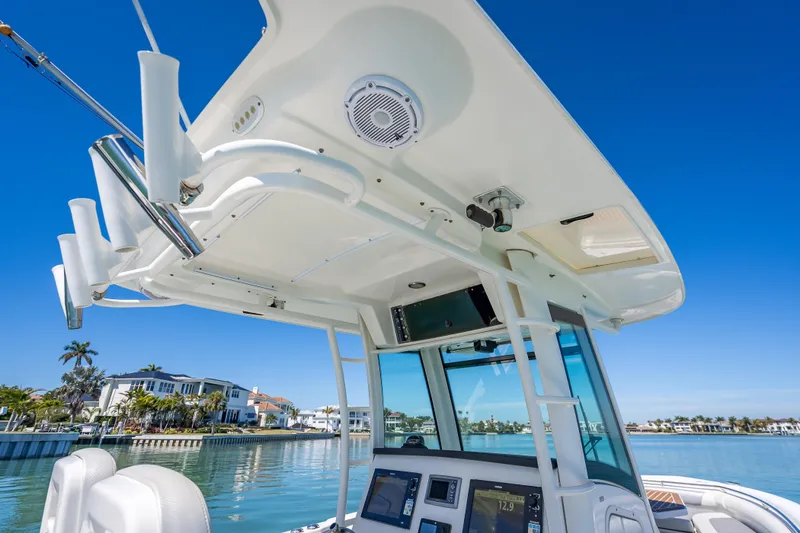 Slide: The Image of 2013 Boston Whaler 320 Outrage boat interior with electronics, rod holders, and clear blue sky. - 28