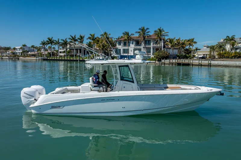 Slide: The Image of 2013 Boston Whaler 320 Outrage boat on calm water, with palm trees and luxury homes in background. - 5