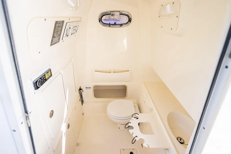 Slide: The Image of 2013 Boston Whaler 320 Outrage cabin interior with toilet and storage compartments. - 50