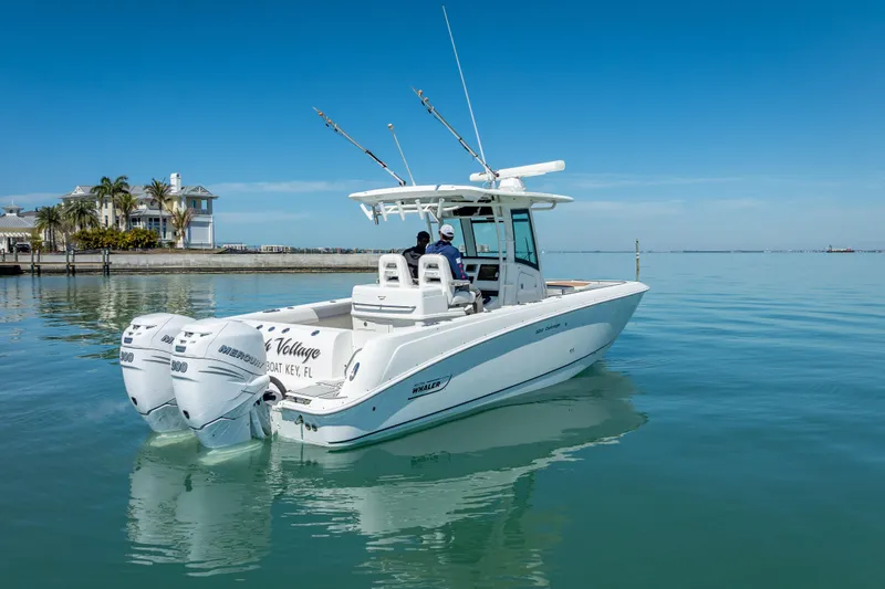 Slide: The Image of 2013 Boston Whaler 320 Outrage boat on calm water near a coastal home. - 7