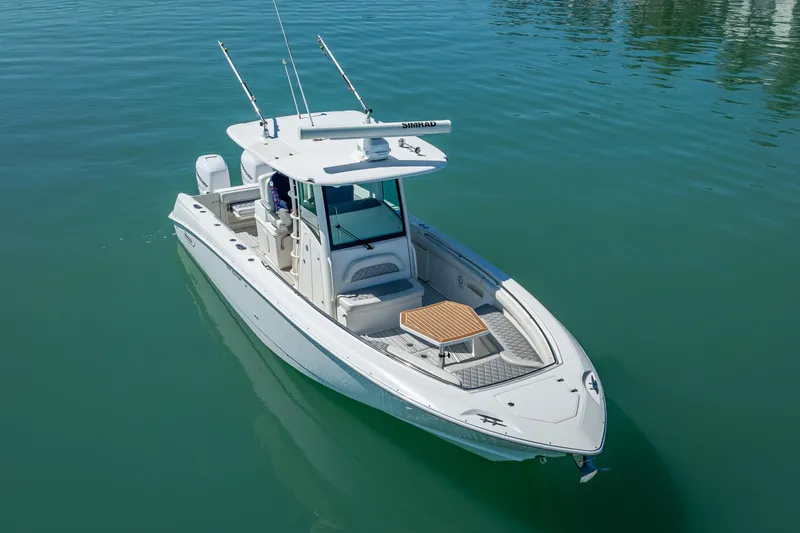 Slide: The Image of 2013 Boston Whaler 320 Outrage boat on calm water, featuring fishing rods and a spacious deck. - 9