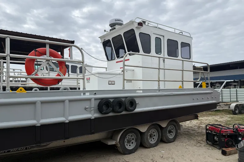 Slide: The Image of Custom Aluminum Work Boat 34x10, 2010 model, docked with safety equipment and overcast sky. - 4