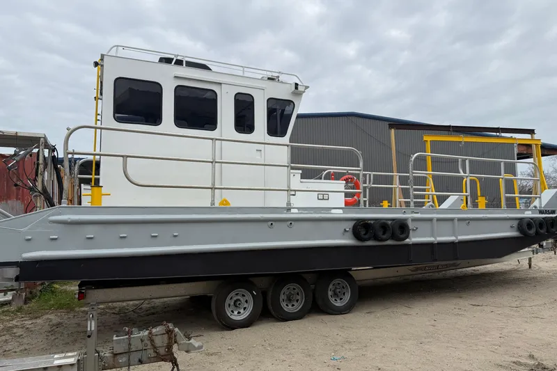 Slide: The Image of Custom Aluminum Work Boat 34x10, 2010 model, on trailer, docked outdoors. - 7