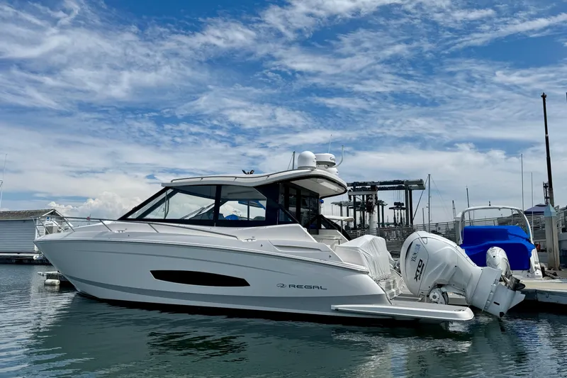 Slide: The Image of 2026 Regal 36 XO boat docked at marina under blue sky. - 11