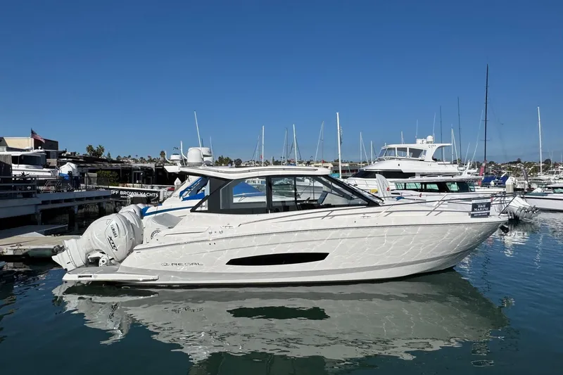 Slide: The Image of 2026 Regal 36 XO yacht docked in marina, clear blue sky, calm water. - 2