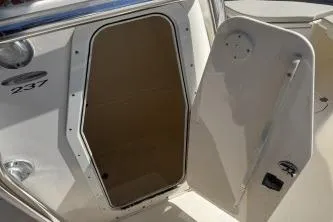 Slide: The Image of 2022 Cobia 237 Center Console boat interior door open, showcasing storage space. - 12
