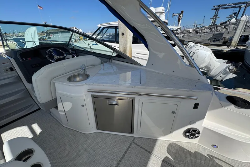 Slide: The Image of 2026 Regal 33 XO boat interior with sink, counter, and steering wheel at marina. - 24