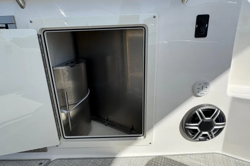 Slide: The Image of Open storage compartment on 2026 Regal 33 XO boat with speaker and control panel. - 26
