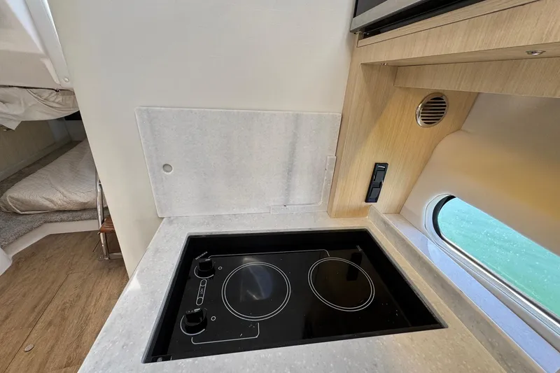 Slide: The Image of Modern kitchen area in 2026 Regal 33 XO boat with electric cooktop and window view. - 80