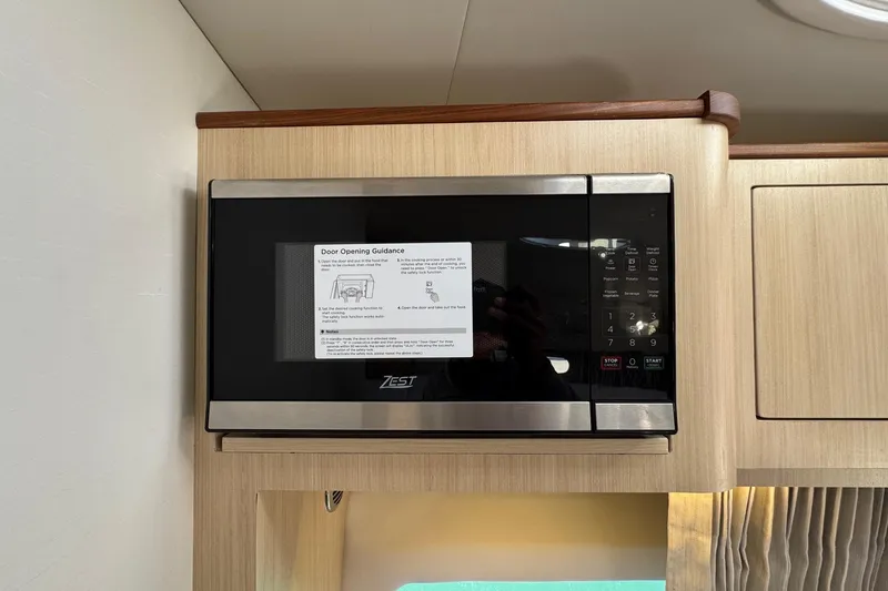 Slide: The Image of Microwave in 2026 Regal 33 XO boat interior, featuring digital controls and wood cabinetry. - 81