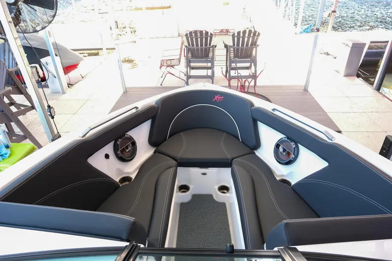 Slide: The Image of 2020 MasterCraft XT25 boat interior with black seating and speakers, dockside view. - 11