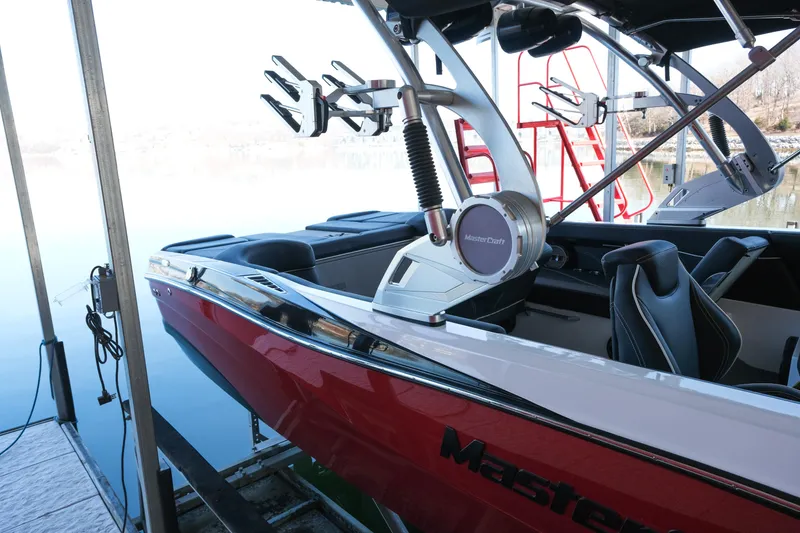 Slide: The Image of 2020 MasterCraft XT25 boat with red exterior and sleek design docked by the water. - 20