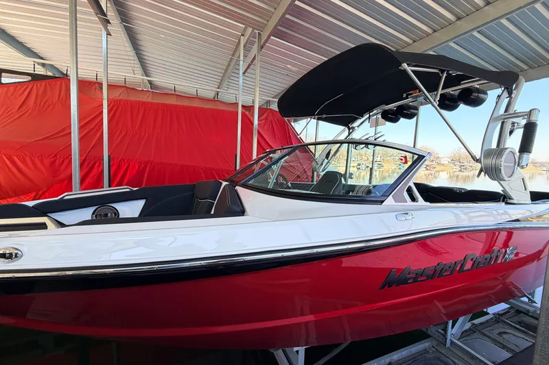 Slide: The Image of 2020 MasterCraft XT25 boat docked under a metal canopy, featuring a sleek red and white design. - 22