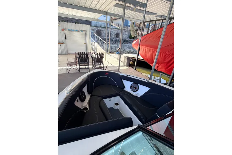 Slide: The Image of 2020 MasterCraft XT25 boat interior with black seating under a covered dock. - 26