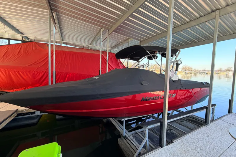 Slide: The Image of 2020 MasterCraft XT25 boat in dock, covered, with red and black design. - 29