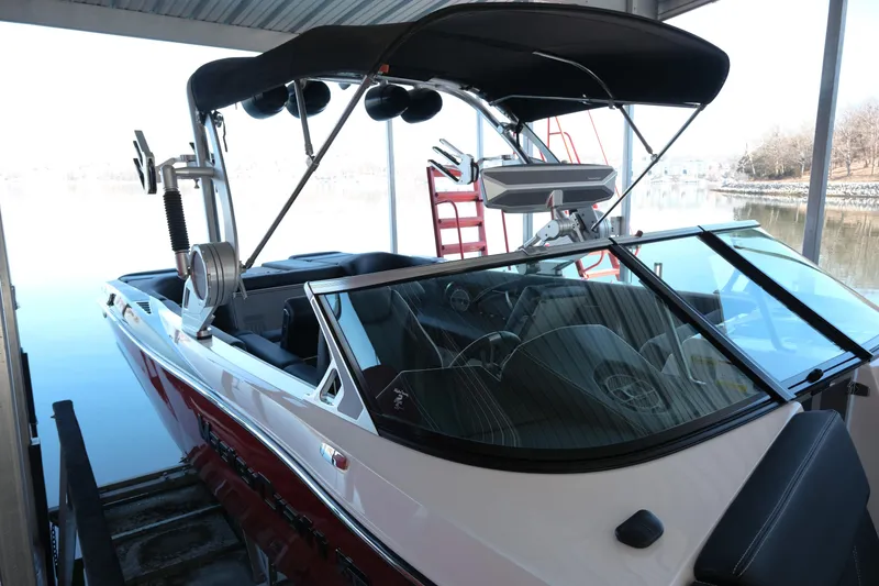Slide: The Image of 2020 MasterCraft XT25 boat docked under a canopy on a calm lake. - 34