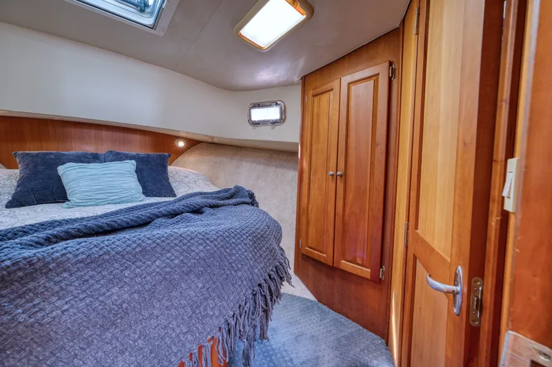 Slide: The Image of Interior of 2005 Mainship 400 Trawler with cozy bed and wooden cabinets. - 25