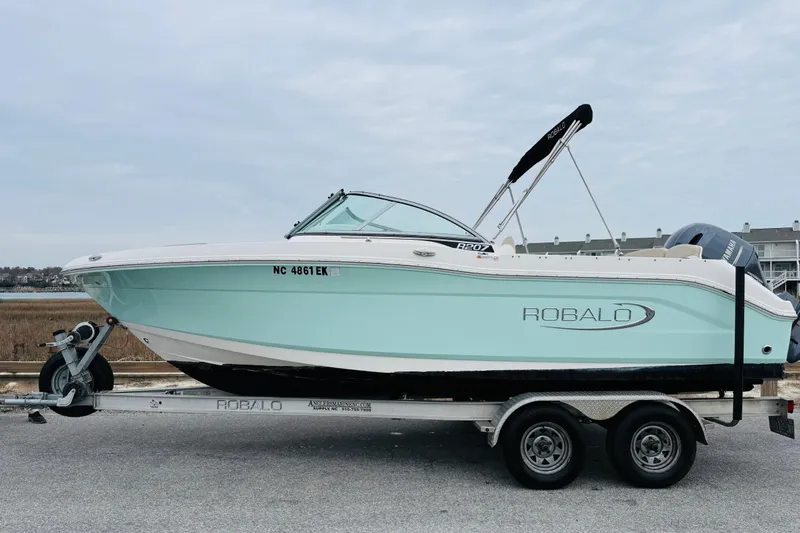Slide: The Image of 2019 Robalo R207 Dual Console boat on trailer, light blue hull, parked outdoors. - 3
